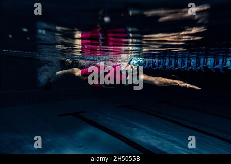 Unterwasseraufnahmen. Eine Schwimmerin trainiert im Hallenbad. Unterwasseransicht der Schwimmbewegungen Details. Stockfoto