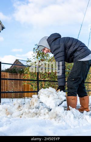 Ein junger Mann, der den Fußweg von Schnee und Eis räumte, um es bei starkem Schneefall sicher zu gehen. Wintersicherheit, Schneeräumung und Eiskonzept Stockfoto