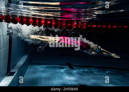 Unterwasseraufnahmen. Eine Schwimmerin trainiert im Hallenbad. Unterwasseransicht der Schwimmbewegungen Details. Stockfoto