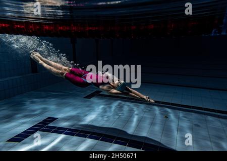 Unterwasseraufnahmen. Eine Schwimmerin trainiert im Hallenbad. Unterwasseransicht der Schwimmbewegungen Details. Stockfoto