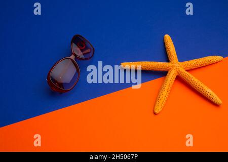 Seesterne und Sonnenglas auf blauem und orangefarbenem Hintergrund Stockfoto