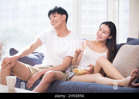 Glückliches junges Paar vor dem Fernseher zu Hause Stockfoto