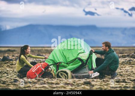 Camping Menschen Outdoor-Lifestyle paar Touristen, die ein Zelt in der Natur Lansdcape in der Dämmerung. Camper mit Rucksäcken, die ihren Campingplatz einrichten Stockfoto