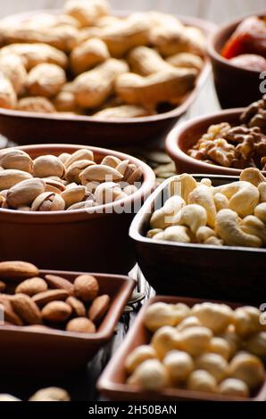 Verschiedene Nüsse und Samen in Tonschüsseln auf Holzküche Tabelle Stockfoto