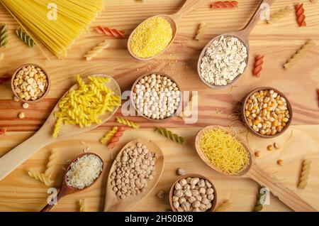 Flat Lay Food Hintergrund aus Hülsenfrüchten Getreide Nudeln und Körner in Holzlöffeln auf Küchentisch Stockfoto