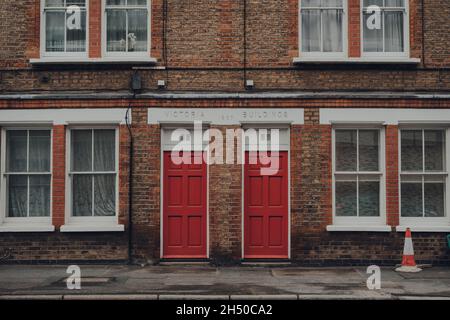 London, Großbritannien - 17. Oktober 2021: Traditionelle rote Eingangstüren an einem Apartmentblock in Victoria-Gebäuden in Southwark, London. Die Türen sind in hellen Farben Stockfoto