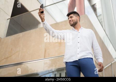 Junger gutaussehender hispanischer Mann nimmt Selfie mit Smartphone im Freien. Hochwertige Fotos Stockfoto