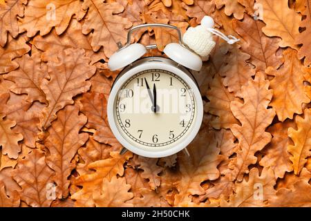 Draufsicht auf Wecker und herbstliche Eichenblätter. Stockfoto