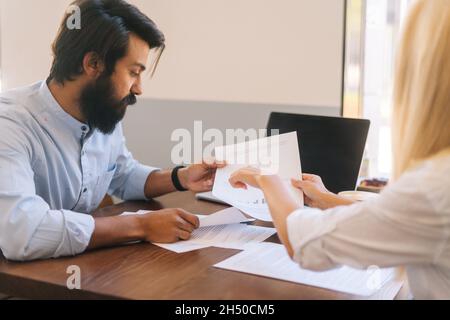 Nahaufnahme von einer attraktiven jungen Geschäftsführerin, die mit einem männlichen Kollegen über Geschäftsaufgaben spricht. Stockfoto