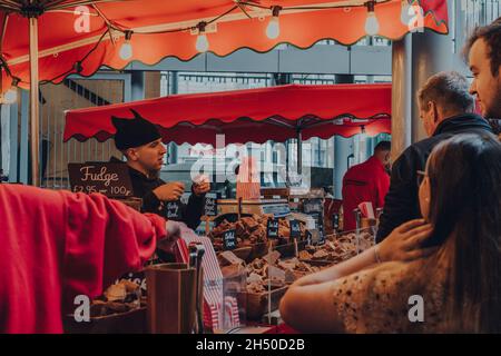 London, Großbritannien - 17. Oktober 2021: Verkäufer und Kunden an einem Fudge-Stand im Borough Market, einem der größten und ältesten Lebensmittelmärkte in London, wählen sich aus Stockfoto