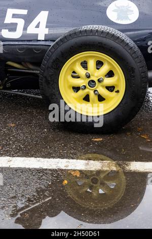 Detailbild Hinterrad und Rennnummer eines 1961 Lola-Ford Mk3 mit Spiegelung in einer Pfütze. Goodwood 78. Mitgliederversammlung. Stockfoto