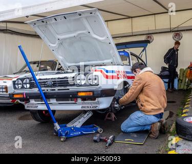 Mechaniker bei der Vorbereitung des Ford Capri III 3.0S von Mark Fowler 1979 in der Fahrerlager-Garage bei Goodwood 78. Mitgliederversammlung, Sussex, Großbritannien. Stockfoto