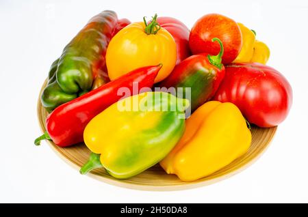 Anordnung von bunt frisch sortierten Paprika und Tomaten in Holzplatte auf weißem Hintergrund. Studio Photo Stockfoto