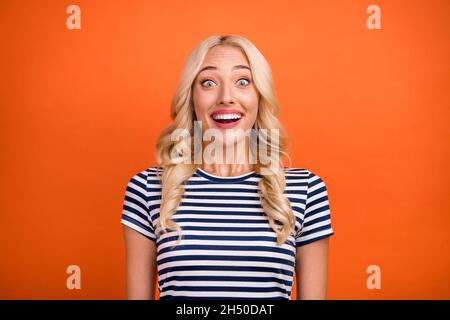 Portrait von attraktiven erstaunt girlish fröhlich Mädchen gute Nachrichten Reaktion isoliert über lebendige orange Farbe Hintergrund Stockfoto