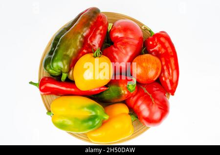 Anordnung von bunt frisch sortierten Paprika und Tomaten in Holzplatte auf weißem Hintergrund. Studio Photo Stockfoto
