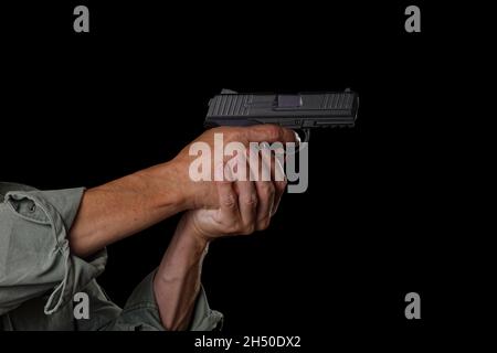 Männliche Hände halten eine Pistole und zielen auf das Ziel. Isoliert auf Schwarz. Stockfoto