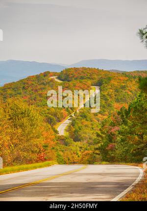 Talimena malerische Nebenstraße, die sich auf dem Bergkamm schlängelt, mit Bäumen in Herbstfarben und trübendem Himmel Stockfoto