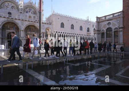 In Venedig, Italien, am 4. Dezember 2021, laufen Menschen auf einem überfluteten Markusplatz während des Wasseraufwands. (MVS) Stockfoto