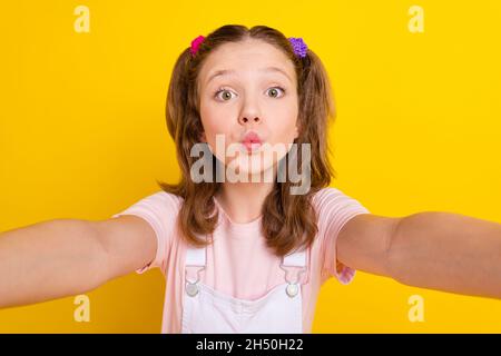 Foto Porträt schulmädchen pouted Lippen unter Selfie isoliert hellen gelben Hintergrund Stockfoto