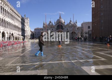 In Venedig, Italien, am 4. Dezember 2021, laufen Menschen auf einem überfluteten Markusplatz während des Wasseraufwands. (MVS) Stockfoto