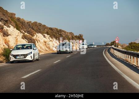 Kas, Türkei - 08. 25. 2021: Autos fahren auf einer Autobahn in Kas, Türkei. Fahren Sie an der Küste in der Nähe der Berge vorbei. Stockfoto