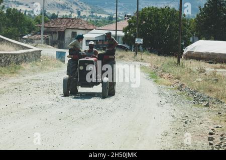 Antalya, Türkei - 08. 25. 2021: Alter oranger Traktor der Marke Turk Fiat fährt mit drei Wokern Stockfoto