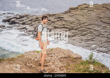 Männlicher Tourist auf dem Hintergrund der schönen Felsen und das Meer. Wanderkonzept. Tobizin Umhang. Wladiwostok, Insel Russky. Japanisches Meer. Primorje Stockfoto