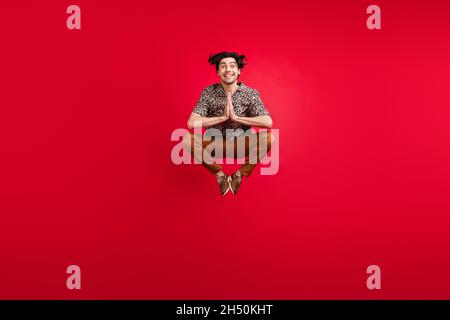 Foto in voller Größe von funky lustig fröhlich lächelnden jungen Mann springen halten Hände in Erwartung isoliert auf rotem Hintergrund Stockfoto