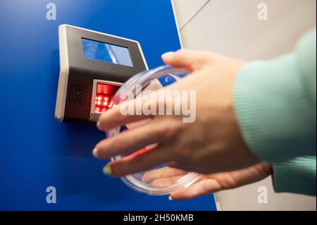 Preisscanner für Barcodes in Nahaufnahme an der Wand in einem Geschäft. Die gesichtslose Käuferin überprüft selbständig den Wert der Ware. Stockfoto