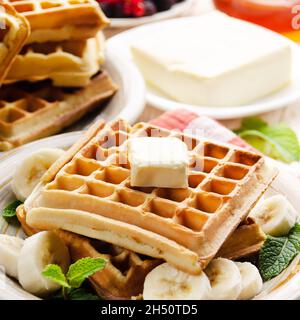 Belgische Waffeln serviert mit Butter Banane Minze Blatt und Sirup Stockfoto