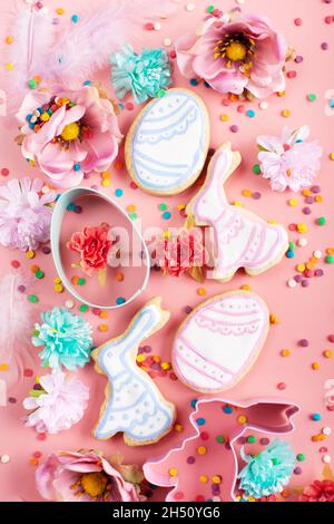 Zuckerstreuseln, Ausstechformen, Ostergarnierte Kekse in Form von Ei und Kaninchen auf rosa Hintergrund. Flaches Lay-Mockup Stockfoto