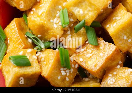 Flacher Lay Hintergrund von Nahaufnahme von knusprig gebratenen Tofu-Stücken mit Schnittlauch und Sesam Stockfoto