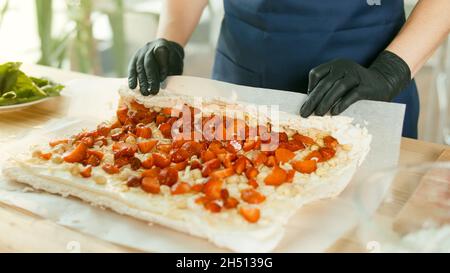 Der Konditormeister bereitet einen Kuchen mit Buttercreme, Nüssen und Erdbeeren zu. Stockfoto