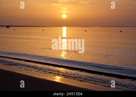 Große gelbe Sonne untergeht über der Meeresoberfläche. Stockfoto