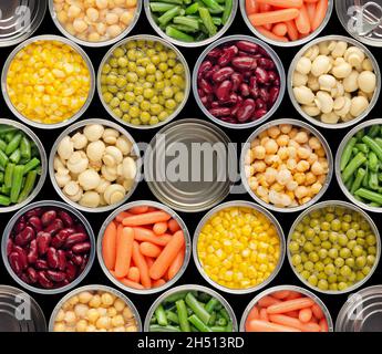 Nahtloser Hintergrund von Lebensmitteln aus geöffneter Dose Kichererbsen, grünen Sprossen, Karotten, Mais, Erbsen, Bohnen und Pilze auf schwarzem Hintergrund Stockfoto