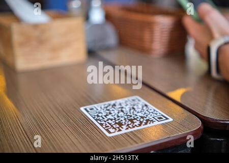 Nahaufnahme der Gäste, die eine Mahlzeit im Restaurant bestellen, während der QR-Code mit dem Mobiltelefon gescannt wird, um ein Online-Menü zu erhalten. Stockfoto