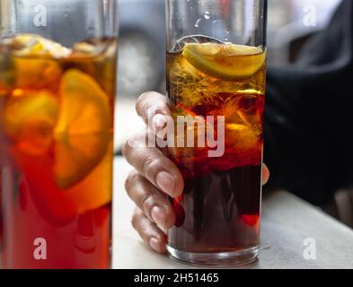 Frauenhand hält ein Highball-Glas mit Wermut und Eis. Roter Wermut auf der Terrasse einer Bar, La Rja, Spanien. Stockfoto