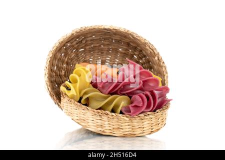 Ungekochte, farbige Fusilli-Pasta mit Strohschalen, Nahaufnahme, isoliert auf Weiß. Stockfoto