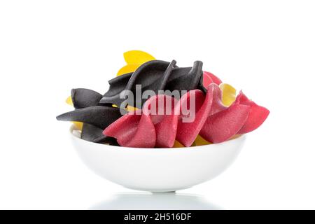 Ungekochte, farbige Fusilli-Pasta mit Keramikgeschirr, Nahaufnahme, isoliert auf Weiß. Stockfoto