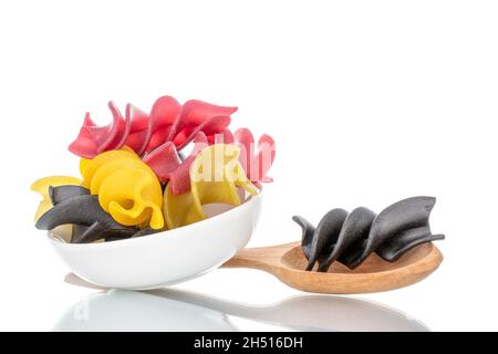 Ungekochte, farbige Fusilli-Pasta mit Keramikschale und Holzlöffel, Nahaufnahme, isoliert auf Weiß. Stockfoto