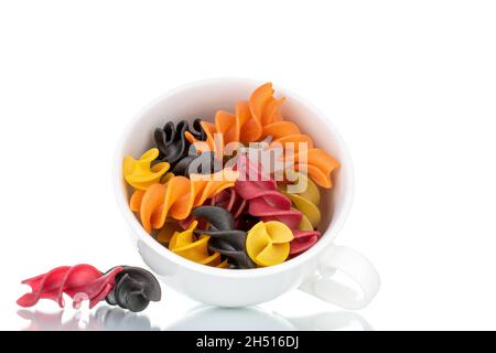 Ungekochte, farbige Fusilli-Pasta mit Keramikgeschirr, Nahaufnahme, isoliert auf Weiß. Stockfoto