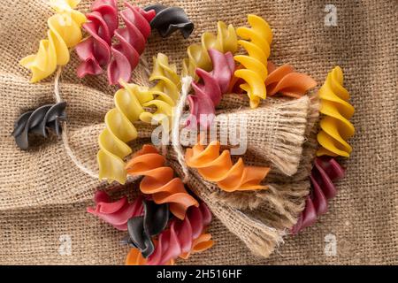 Rohe, farbige Fusilli-Pasta auf dem Sacken, Nahaufnahme, Draufsicht. Stockfoto