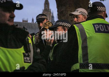 Westminster, London, Großbritannien. November 2021. Eine junge Frau wird von der Polizei weggeführt, nachdem sie anscheinend versucht hat, ein Feuerwerk anzuzünden. Die Demonstranten des jährlichen Millionen-Maske-Marsches mischen sich heute Nachmittag und Abend auf dem Parliament Square in Westminster mit Anti-Lockdown- und Anti-Impfdemonstranten, einige auch in Guy Fawkes-Masken. Es werden Flare und einige Feuerwerke angezündet, was die Polizei dazu veranlasst hat, eine vorsichtige Haltung einzunehmen, mit einer starken Polizeipräsenz in Westminster heute Abend. Kredit: Imageplotter/Alamy Live Nachrichten Stockfoto