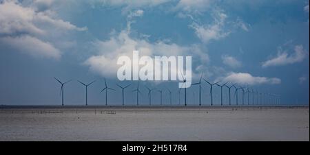 Moderner Windmühlenpark am IJsselmeer in den Niederlanden. Zerklüftete Wolken im Hintergrund. Stockfoto