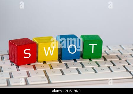 Die Buchstaben SWOT stehen für Stärken, Schwächen, Chancen und Bedrohungen. Diese Buchstaben sind weiß auf roten, gelben, blauen und grünen Blöcken geschrieben Stockfoto