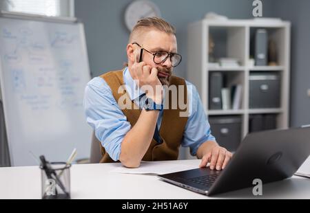 Nachdenklicher Mann, der an einem Laptop arbeitet Stockfoto