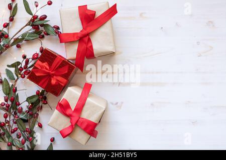 Drei Weihnachtsgeschenke als Bordüre mit roten Beeren und Lichter mit roten Schleifen von oben auf weißem Hintergrund mit Kopierraum Stockfoto