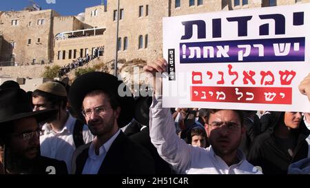 Ein Haredi-Jude hält ein Schild mit der Aufschrift „Judentum ist nur einer, Linke sind viele“, während sich Ultra-orthodoxe Juden während eines Protestes gegen „Frauen der Mauer“ versammeln. Beim Betreten des platzes der Westmauer mit Tora-Rollen in einer langjährigen Kampagne für die Gleichstellung der Geschlechter an dem Ort, der dem jüdischen Volk am 05. November 2021 in Jerusalem, Israel, geweiht ist. The Women of the Wall ist eine feministische Gebetsgruppe, die eine monatliche Gebetsstunde an der Western Wall veranstaltet und immer wieder behauptet hat, dass es keinen einzigen „Brauch des Ortes“ gibt und dass ihr Recht zu beten eine im ISR verankerte Religionsfreiheit ist Stockfoto