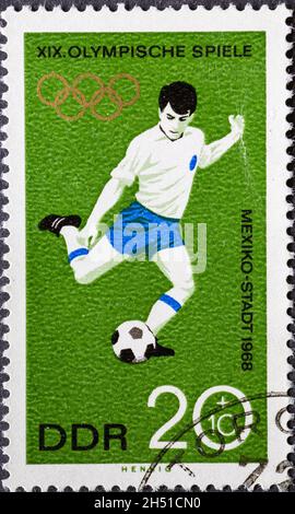 DEUTSCHLAND, DDR - UM 1968: Eine Briefmarke aus Deutschland, DDR mit olympischen Ringen zu den Olympischen Spielen in Mexiko-Stadt 1968: Fußballspieler Stockfoto