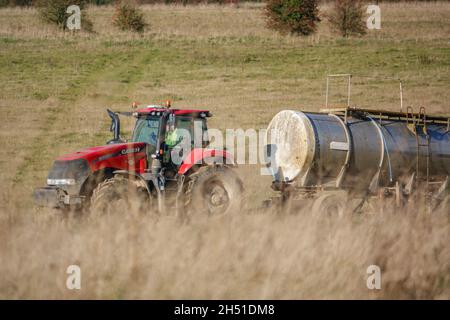 Ein großer Red Case 340 Magnum Traktor schleckt einen 30 Tonnen schweren Wasseranhänger über Ackerland Stockfoto